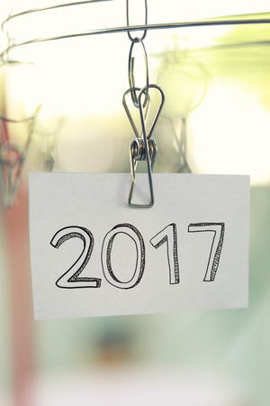 2017 text on white paper notes hanging in a clothesline on green bokeh background.の写真素材