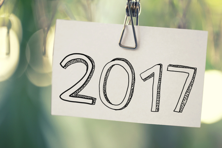 2017 text on white paper notes hanging in a clothesline on green bokeh background.の写真素材