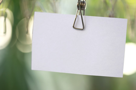 white paper notes hanging in a clothesline on green bokeh background.の写真素材