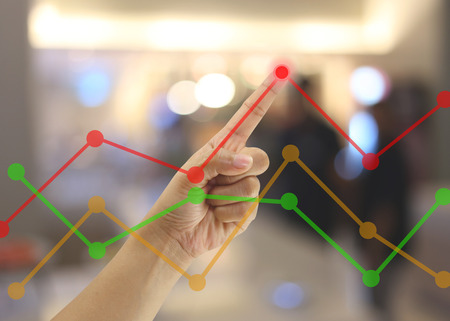 Hand of businessmen point to the highest point on the line graph in concept of business profits in the presentation.の写真素材