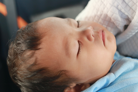 Asian boy is sleeping in his mother's arms,concept of love for mother to baby.の写真素材