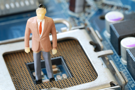 Businessman doll Stand on a computer motherboard in concept of doing business and profiting on technology.の写真素材
