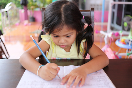 Asian child girl use Pencil write letters on the book in concept of education and learning.の写真素材