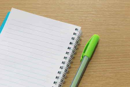 Blank notebook and color pen placed on a brown wood floor for design concept in your work.