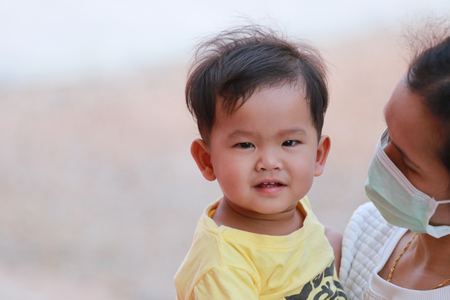 Asian boy in yellow dress in embrace your mother is carrying,concept of health care and love of the family.の写真素材
