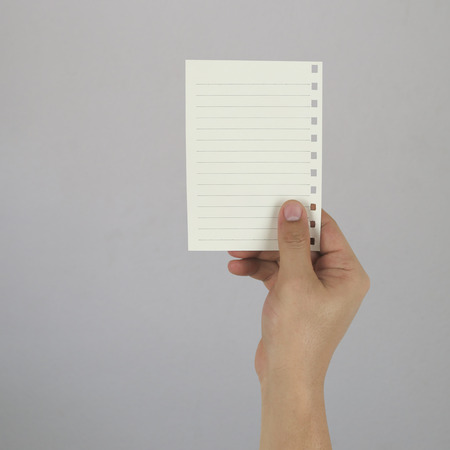 Hand of the businessman holding a empty paper note on gray wall background and have copy space to...