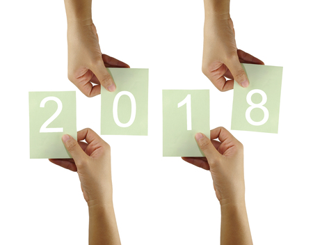 hand of a business woman hold a green paper note and 2018 text isolated on white background.の写真素材