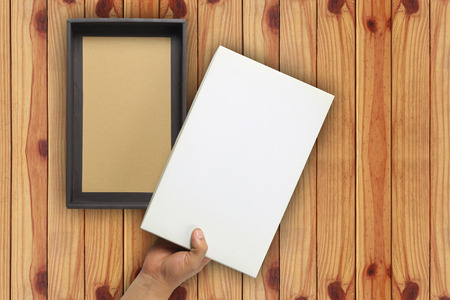 Hand of a businessman opening a white paper box and have copy space to design Concept in your work on brown wooden background.の写真素材