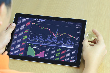 Gold bitcoin in hand of businessman and digital graph in tablet PC,concept of cryptocurrency idea for design in your work.の写真素材
