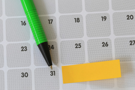 Green pen points to a thirty one number of calendar and have blank yellow note paper for design...