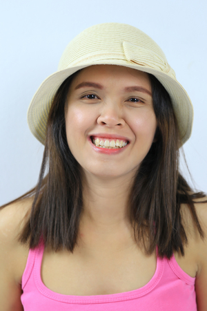 Asian woman of long hair wear hat and smiling happily on gray wall background.の写真素材