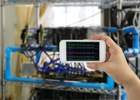 Hand of businessman holding a smartphone in a text of program to mining ETH coin on blur digging...