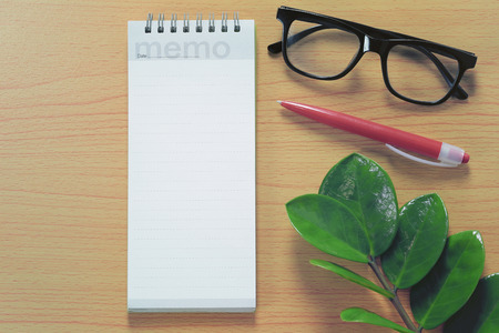 Blank paper note and eyeglasses placed on a brown wooden floor for design in your work concept.の写真素材