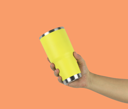 Hand of a man holding a glass yellow of water on Orange color background and have clipping paths function for easy to use design.の写真素材