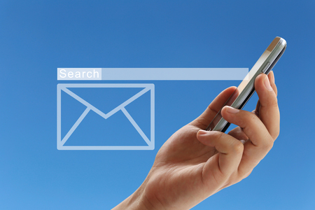 Hand of a businessman holding a smartphone and have white envelope of e-mail symbol on blue background for design in your work.の写真素材