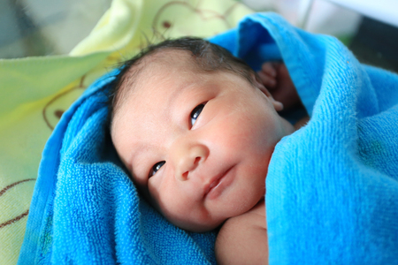 Asian Infant want to sleeping in Blue towel.の写真素材