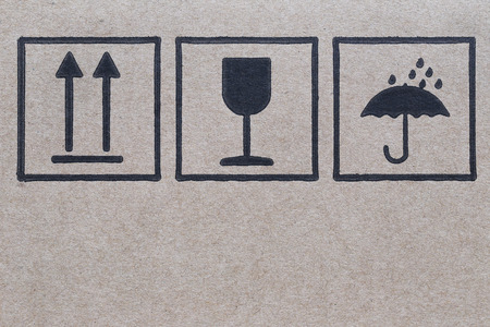 symbol logo beside a brown cardboard box in careful of transportation.の写真素材