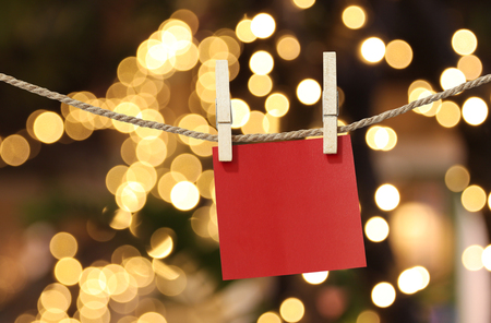 Blank red paper notes hanging on clothesline for design in Christmas Day on bokeh light background,Notepad for design ideas for Important day.の写真素材