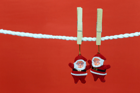 Santa doll hang on the clothesline and have copy space with red background for design in your work concept.の写真素材