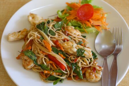 Spicy Stir Fried Spaghetti with Seafood in a white dish on food table restaurant.の写真素材
