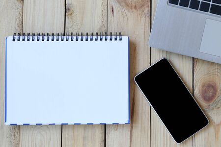 Empty notebook and a blank smartphone placed on a desk for design in your work concept.