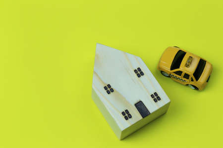 Wooden model house and toy car on yellow paper background and have copy space.の写真素材