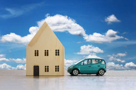 Wooden house and toy cars on the floor concept of having property as a home and car.