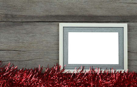 Empty vintage photo frame on wooden floor and red tassels for Christmas and New Year decorations.の写真素材