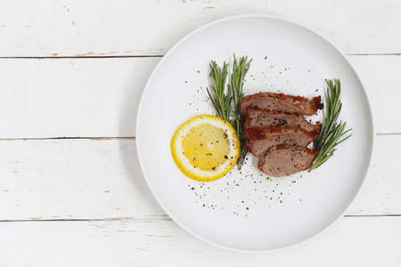 Black Pepper Grilled Pork with lemon in white dish on wooden floor.の写真素材