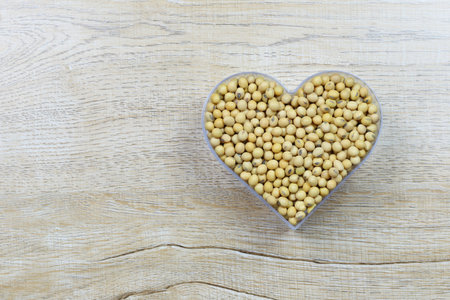 Fresh soybean in a heart shaped mold rests on a wooden table and has a copy space for design in love and valentine day.の写真素材
