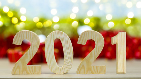 Wooden number of Two thousand twenty one and blur red gift box and Christmas bokeh background for...