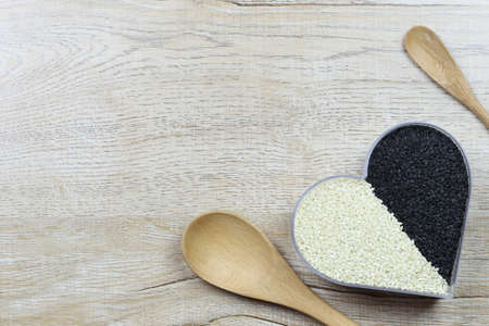 White and black sesame seeds in a heart shaped box and have copy space for design in you love and...
