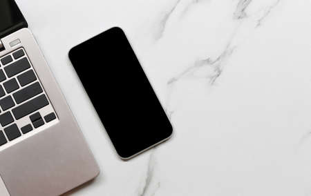 Smartphone of blank screen placed beside the notebook and have clipping paths with screen mobile,...