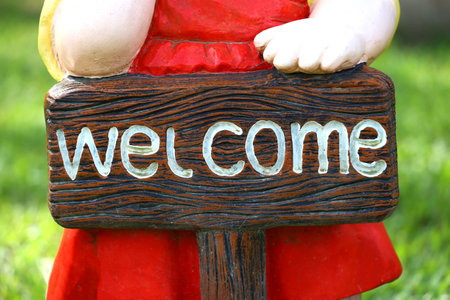 Focus on sign of Welcome letter sign in hand of a stucco doll.の写真素材