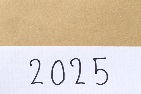 Numbers two thousand twenty-five are hand-written on white art paper background for design in your...