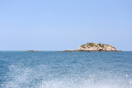 View of the sea with islands in the background and spray from the waves of a speedboat.の写真素材