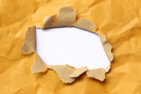 Crumpled and torn brown paper with gaps to reveal the art paper inside, for design in your work.の写真素材