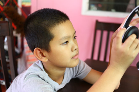 A young boy immersed in music, wearing headphones. This indoor scene captures the joy of listening, showcasing focus and engagement with sound.の写真素材