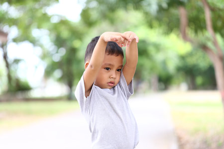 A young boy enjoying nature while stretching outdoors. This image captures the innocence and joy of...