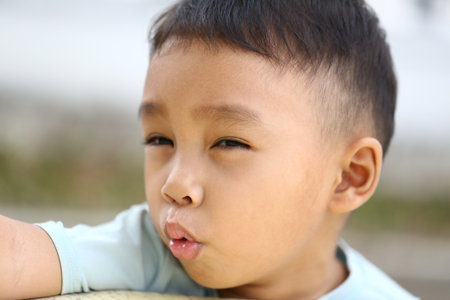 A playful boy makes a funny face outdoors, showcasing his joyful personality. This candid portrait captures the essence of childhood joy and innocence.の写真素材