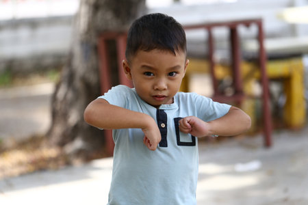 A confident young boy expresses enthusiasm outdoors with playful gestures. This image captures the essence of childhood joy and carefree spirit.の写真素材