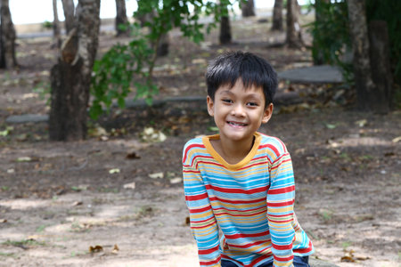A joyful child sits in a park, enjoying nature with a bright smile. The scene captures the essence of childhood exploration and carefree play.の写真素材
