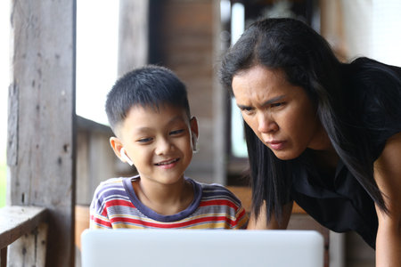 A parent and child share a moment of learning using a laptop, showcasing the joy of digital education and the importance of family interaction at home.の写真素材