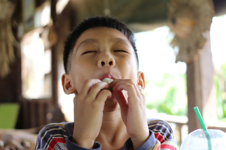 A joyful child delights in a tasty snack outdoors, showcasing a genuine expression of happiness. The...
