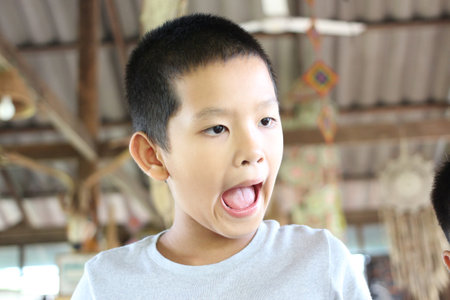 A candid portrait of a young boy expressing surprise and joy in a vibrant indoor environment, capturing the essence of childhood and playfulness.の写真素材