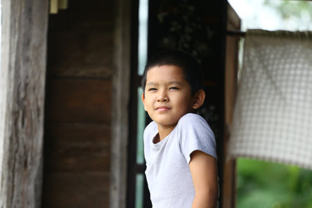 A confident young boy strikes a relaxed pose outdoors, showcasing joy and innocence. The natural setting emphasizes the freshness of childhood and carefree spirit.の写真素材
