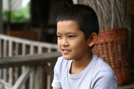 A candid portrait of a young boy sitting outdoors, reflecting joy and innocence. His thoughtful expression captures the essence of childhood and relaxation.の写真素材