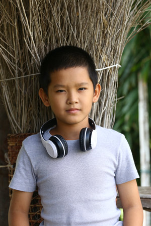A young boy wears headphones and poses confidently in a natural setting, showcasing a blend of youth...