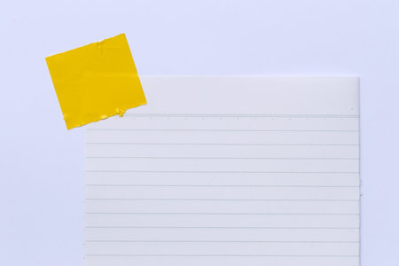 Blank notepad with a Yellow glue tape affixed at the top. Ideal for showcasing creativity, organization, and planning.の写真素材