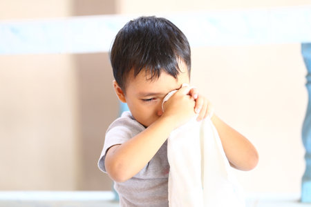 A young boy expresses heartfelt emotions while holding a cloth, capturing a poignant moment of childhood vulnerability and innocence in soft, natural light.の写真素材